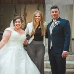 Vor der Kirche steht die Hochzeitssängerin mit dem Brautpaar nach der kirchlichen Trauung