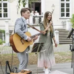 Gitarrist und Sängerin spielen als Duo beim Sektempfang einer Hochzeit
