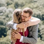Sängerin für Hochzeiten umarmt lachend den Bräutigam nach der standesamtlichen Trauung