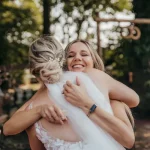 Nach der Trauung umarmt die Hochzeitssängerin lachend die Braut